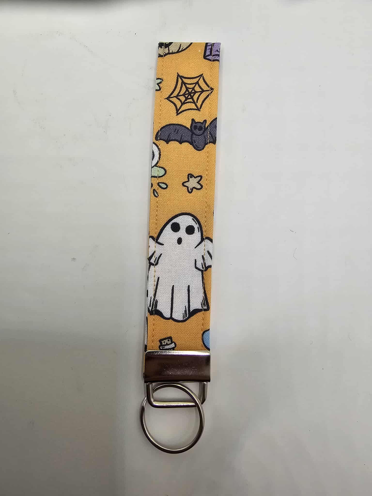 Halloween ghost & bat fabric wristlet key holder on orange backdrop with ghosts, bats, stars and spiderwebs.